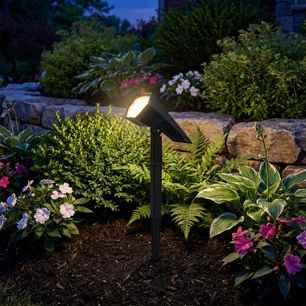Solar spike light glowing in a landscaped garden bed at night